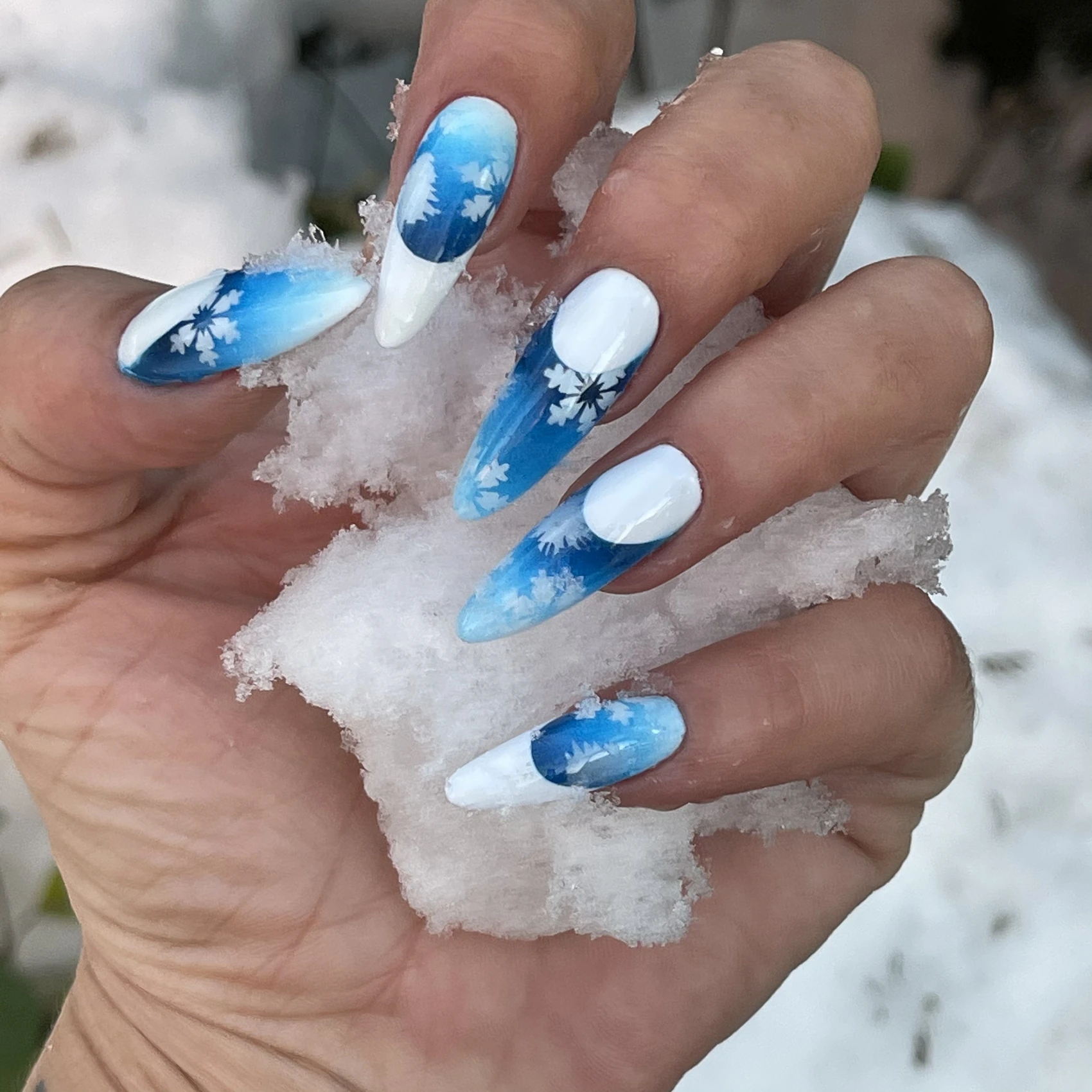 Manicura azul y blanca con degradados de aerografía y motivos de copos de nieve