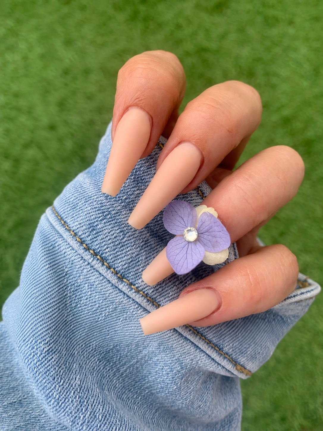 Uñas acrílicas nude con decoración de flor lila del material del curso