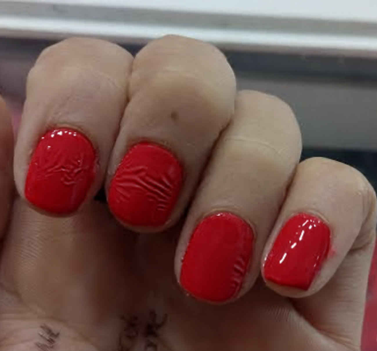 Esmalte rojo con arrugas visibles; color editado con IA