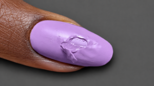 Esmalte lila con defecto superficial; color y encuadre editados con IA