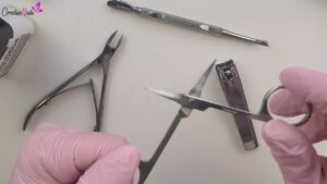Tijeras, alicate, empujador y cortaúñas mostrados sobre la mesa