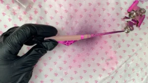 Estructura Nergal rosa y fucsia con franjas y textura geométrica, sostenida con un guante