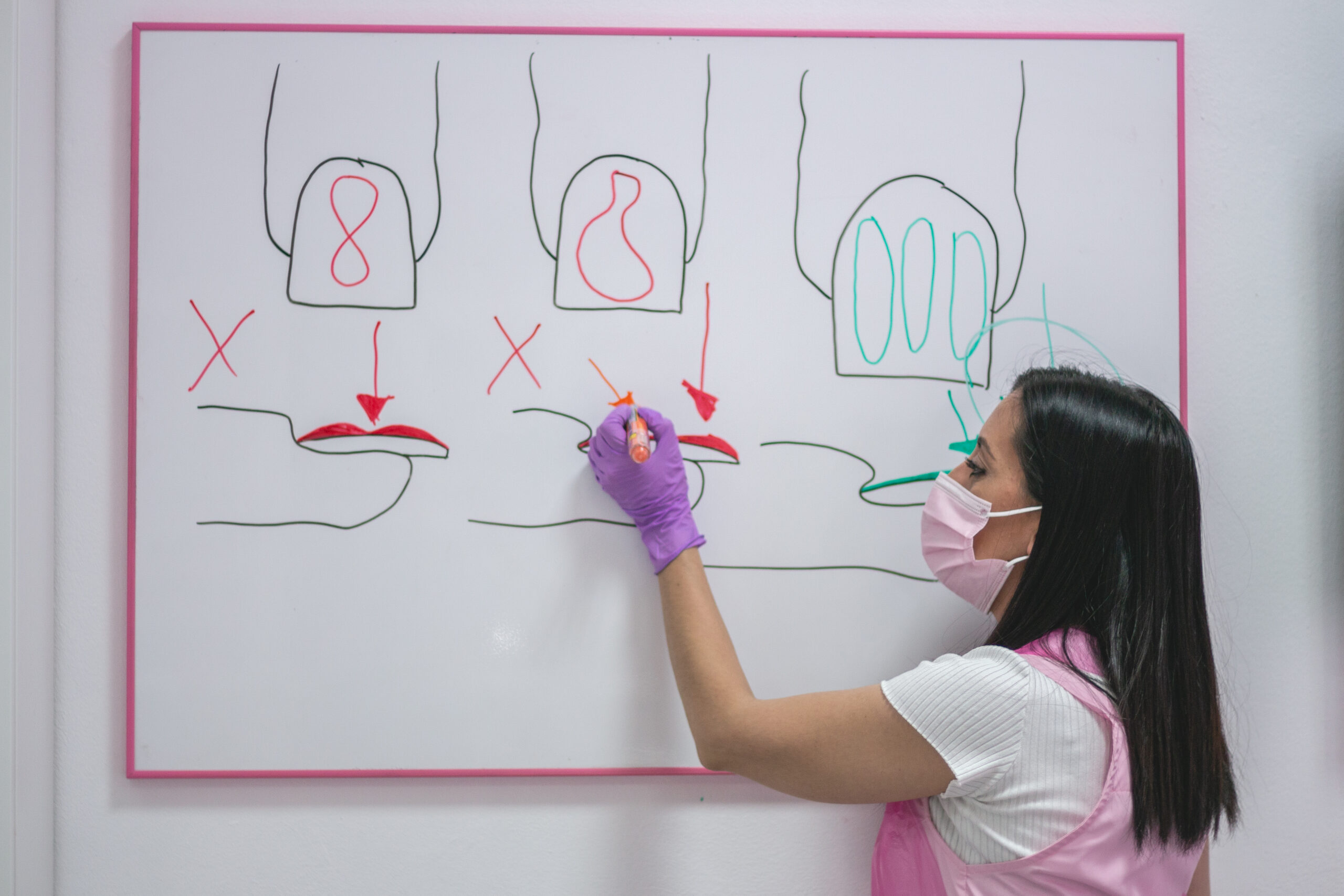 Sara Orozco explica esquemas de uñas en una pizarra durante una clase de manicura