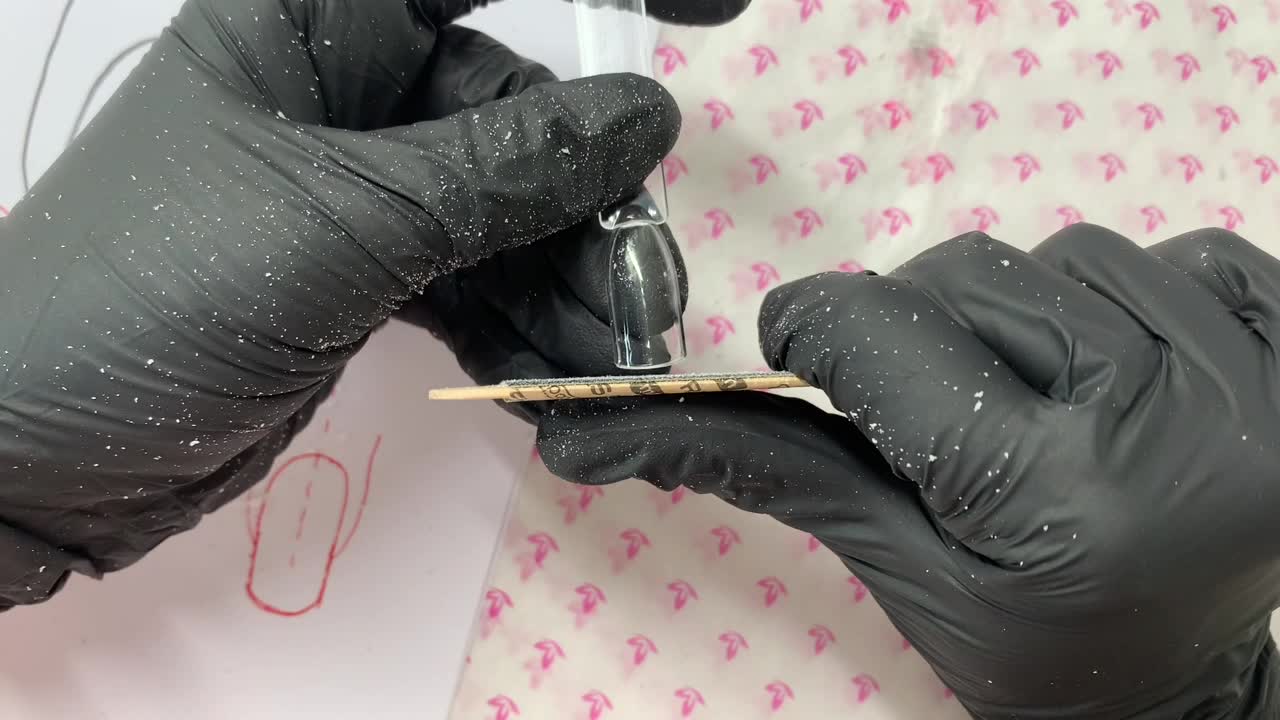 Ejercicio del curso sobre un tip transparente, sostenido con guantes negros mientras una lima se coloca junto al extremo.